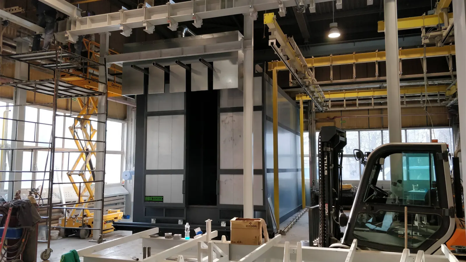 Spray booth installation with a scissor lift and forklift